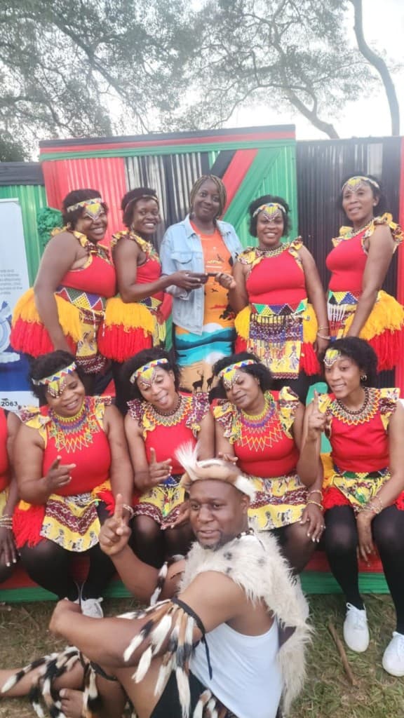 Troupe on stage with Zimbabwe flag colours backdrop